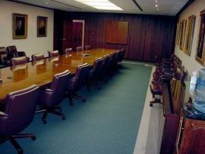 Boardroom at a bank featuring a video screen tastefully enclosed in a wooden cover to blend with the traditional decor.